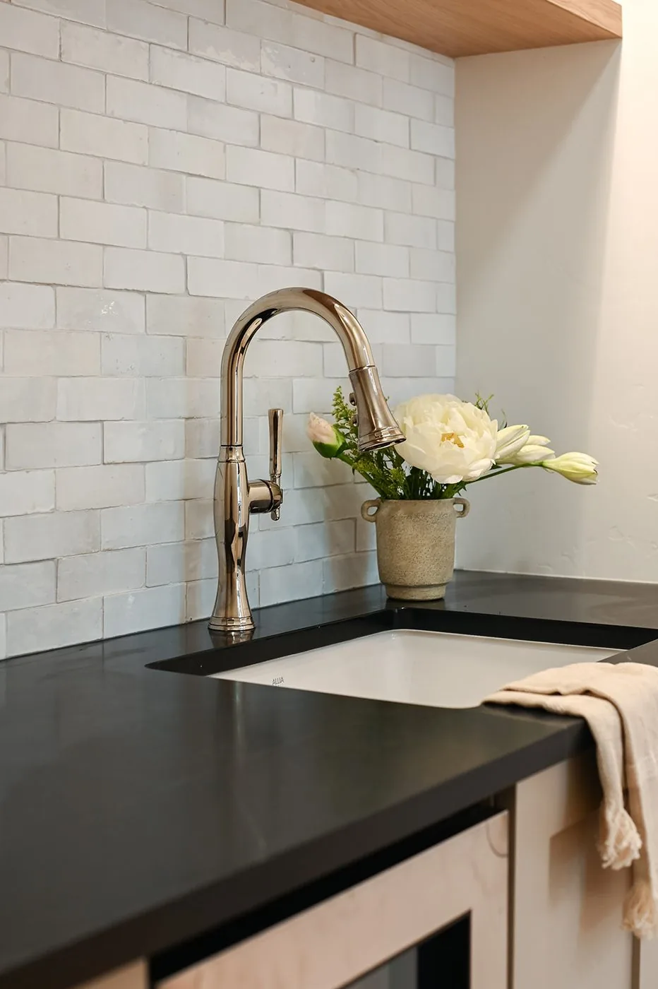 Prep sink detail with honed black stone, handmade tile and a polished faucet
