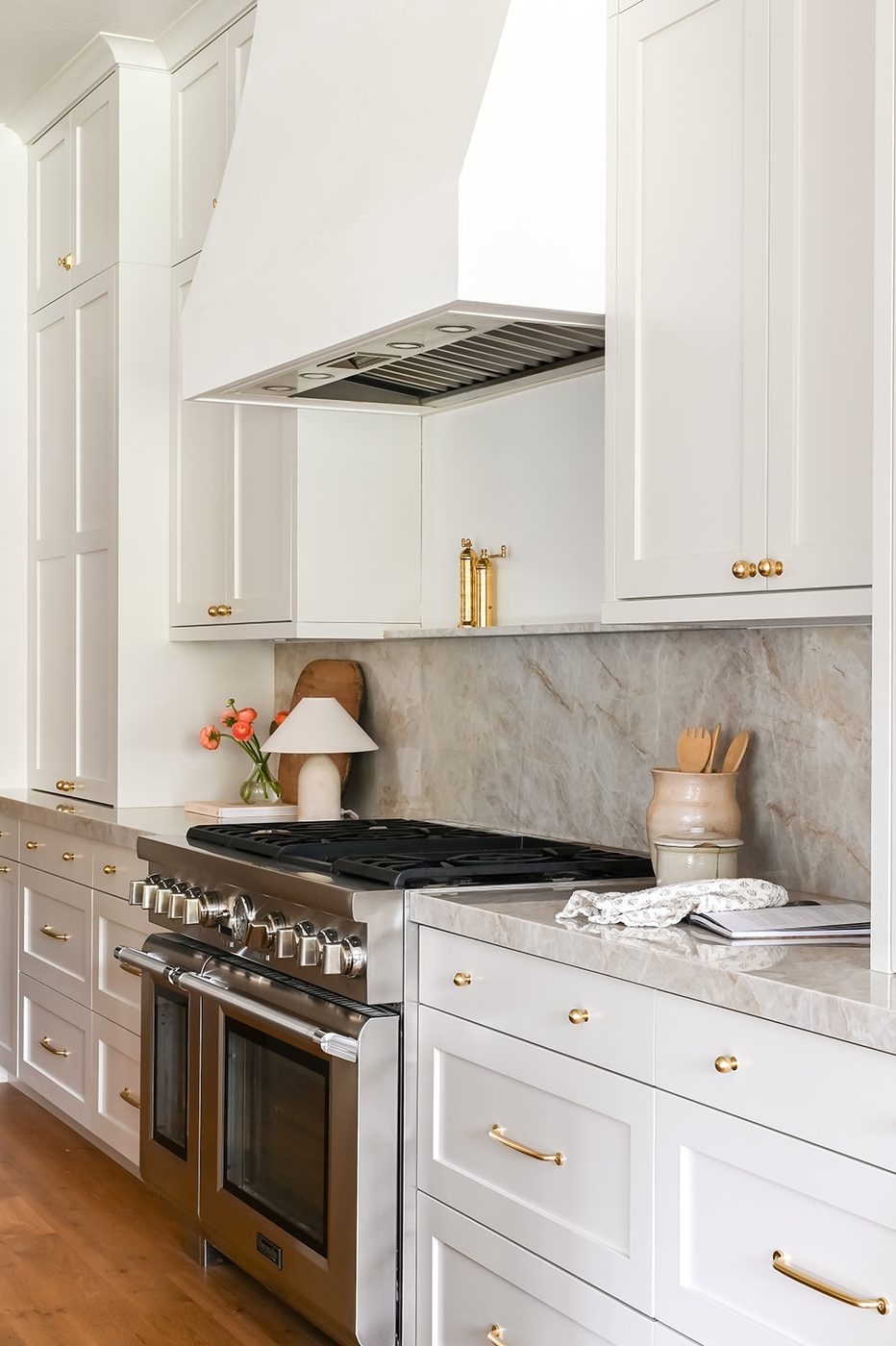 Range wall with a plaster hood, full stone slab backsplash and brass hardware