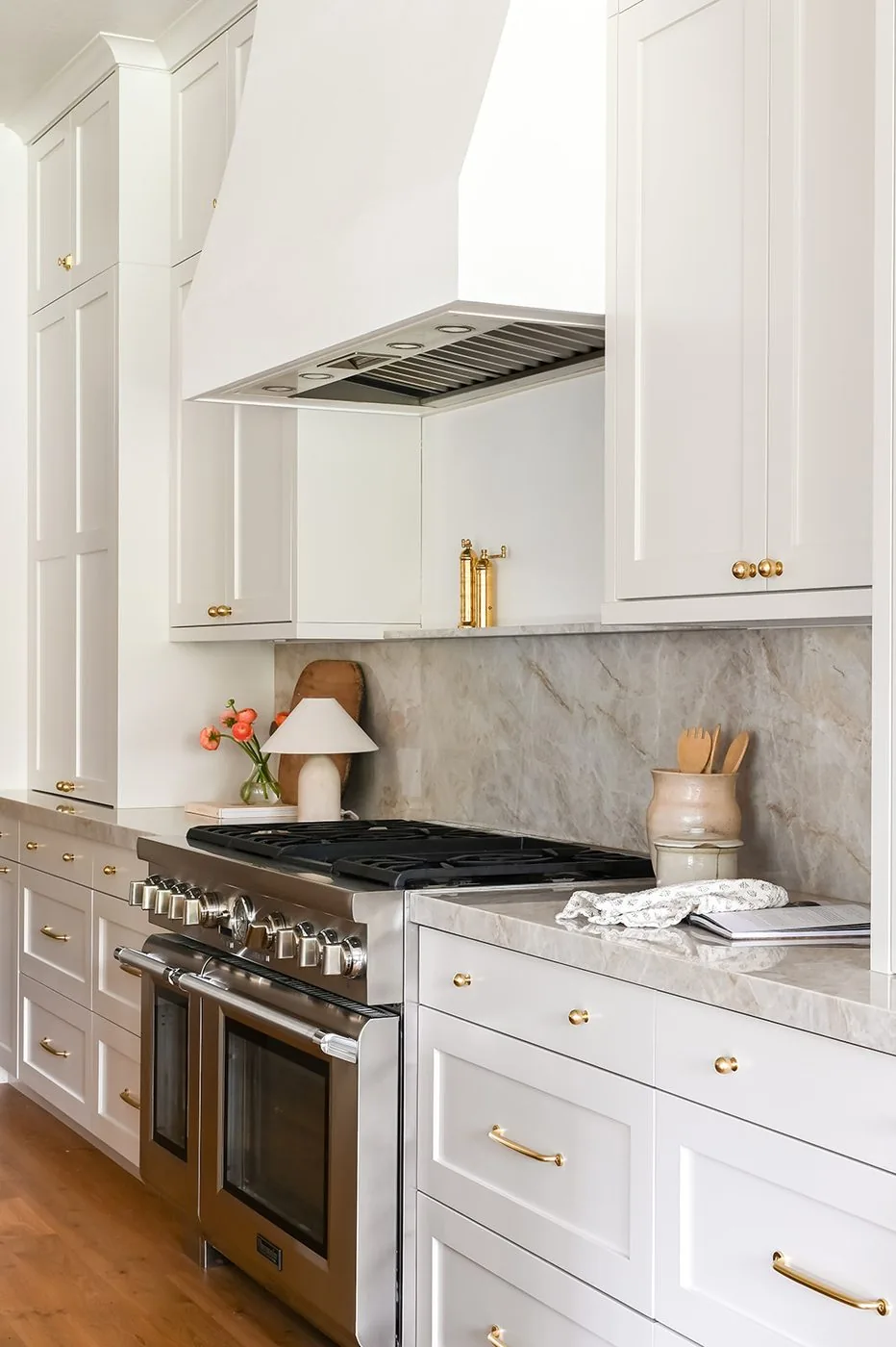 Range wall with a plaster hood, full stone slab backsplash and brass hardware