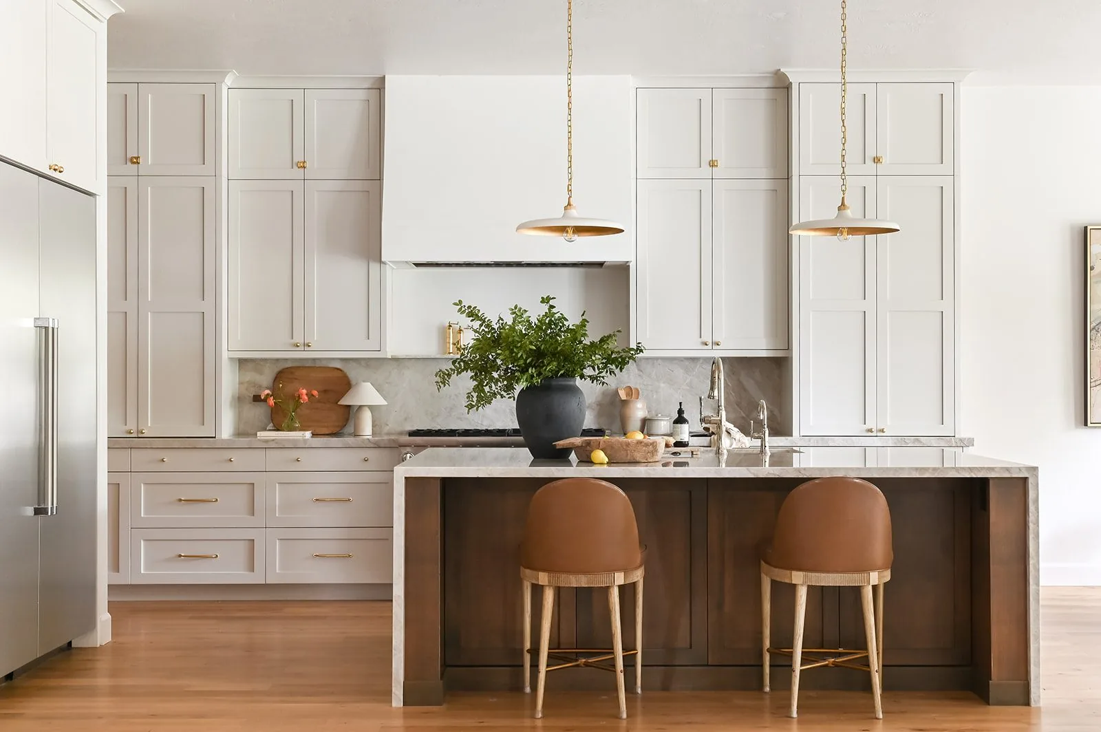 Kitchen with a dark stained island, stone counters and brass pendants