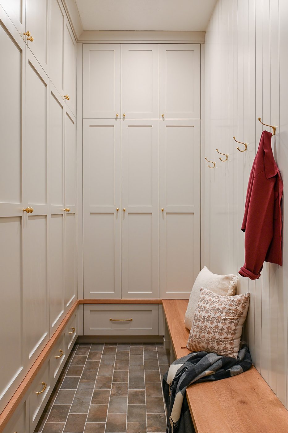 Mudroom with floor to ceiling lockers, an oak bench and brass hooks