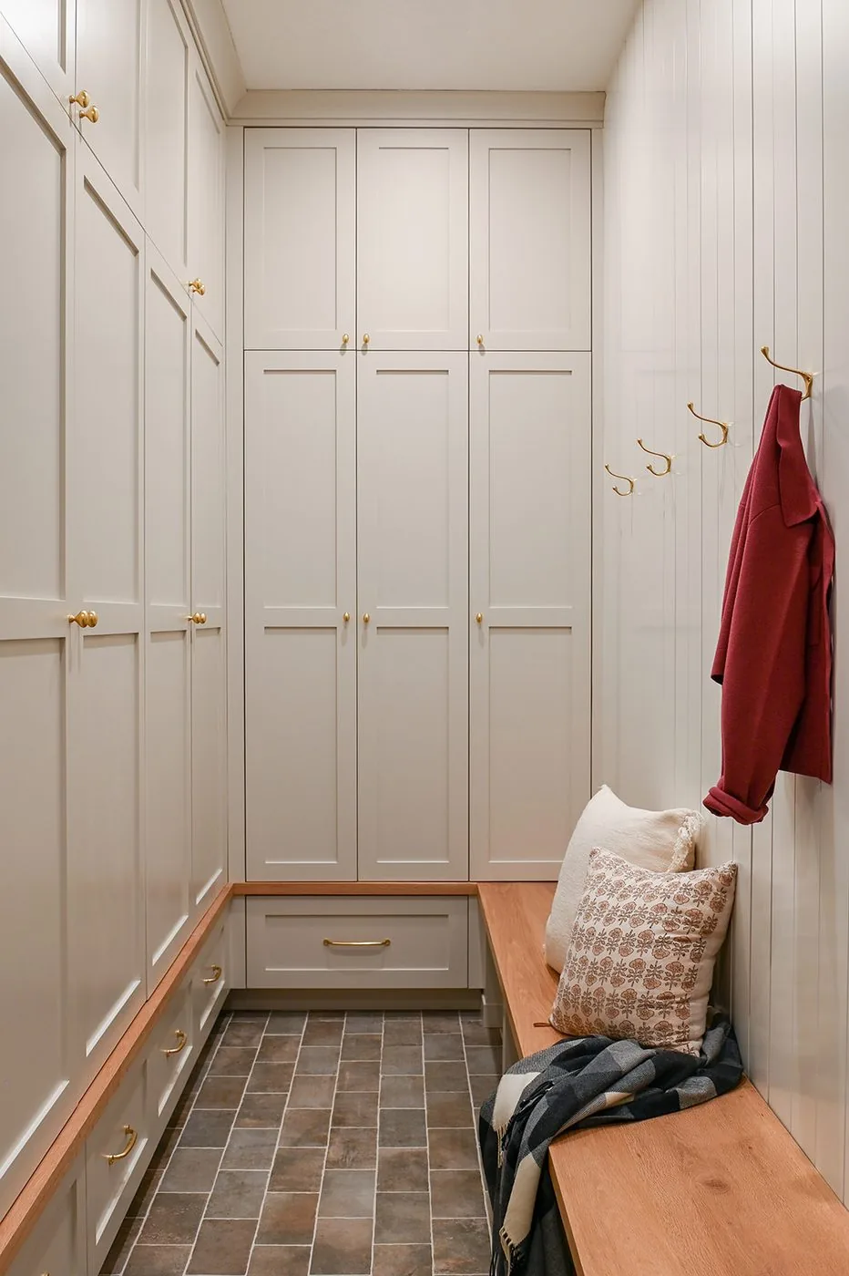 Mudroom with floor to ceiling lockers, an oak bench and brass hooks